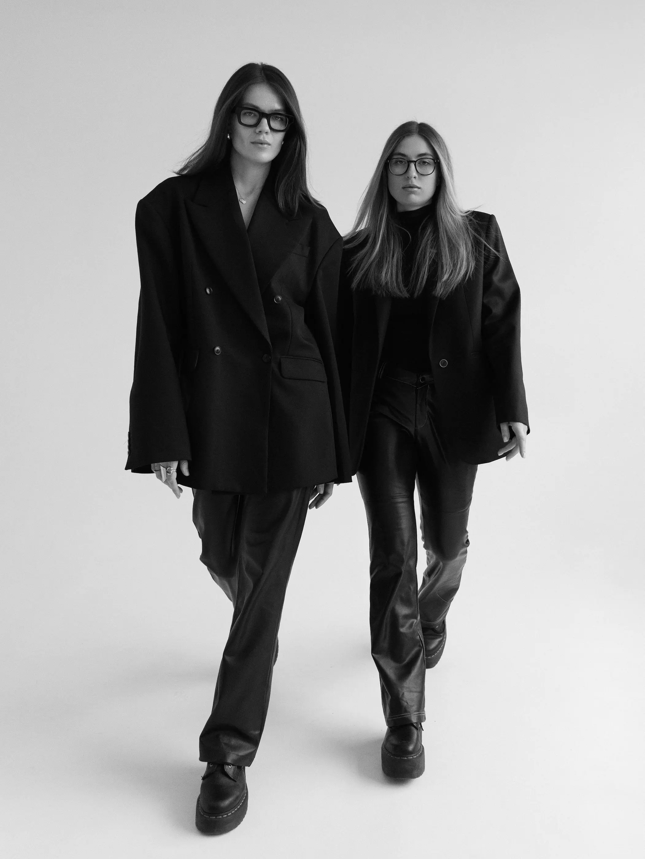 FANDS MARKETING AGENCY — Black and white photo of two women; one is lying on her side looking at the camera, the other is holding a camera up to her face to take a picture.