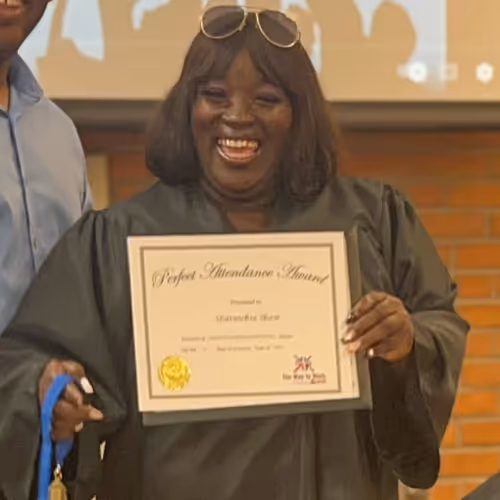 Sharmeka smiles at the camera while holding her diploma