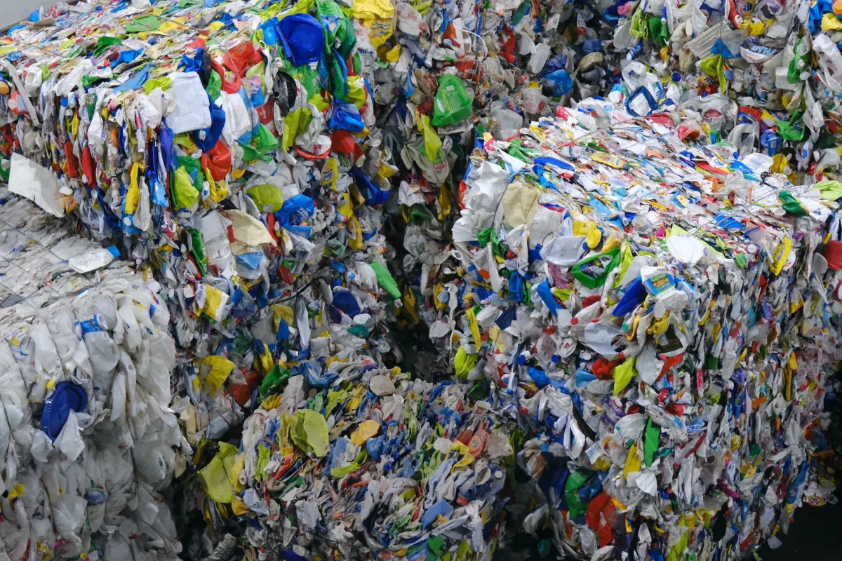 Large compressed bales of colorful plastic waste stacked closely together for recycling.