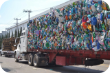 Large semi-truck trailer loaded with compacted colorful recyclable plastic bottles.