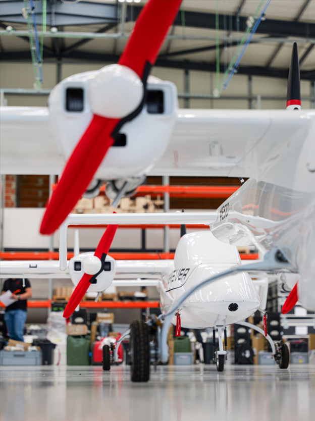 Alaris Pro | Drone with illuminated lights on a landing pad at night in front of a forest fire burning on a hillside.