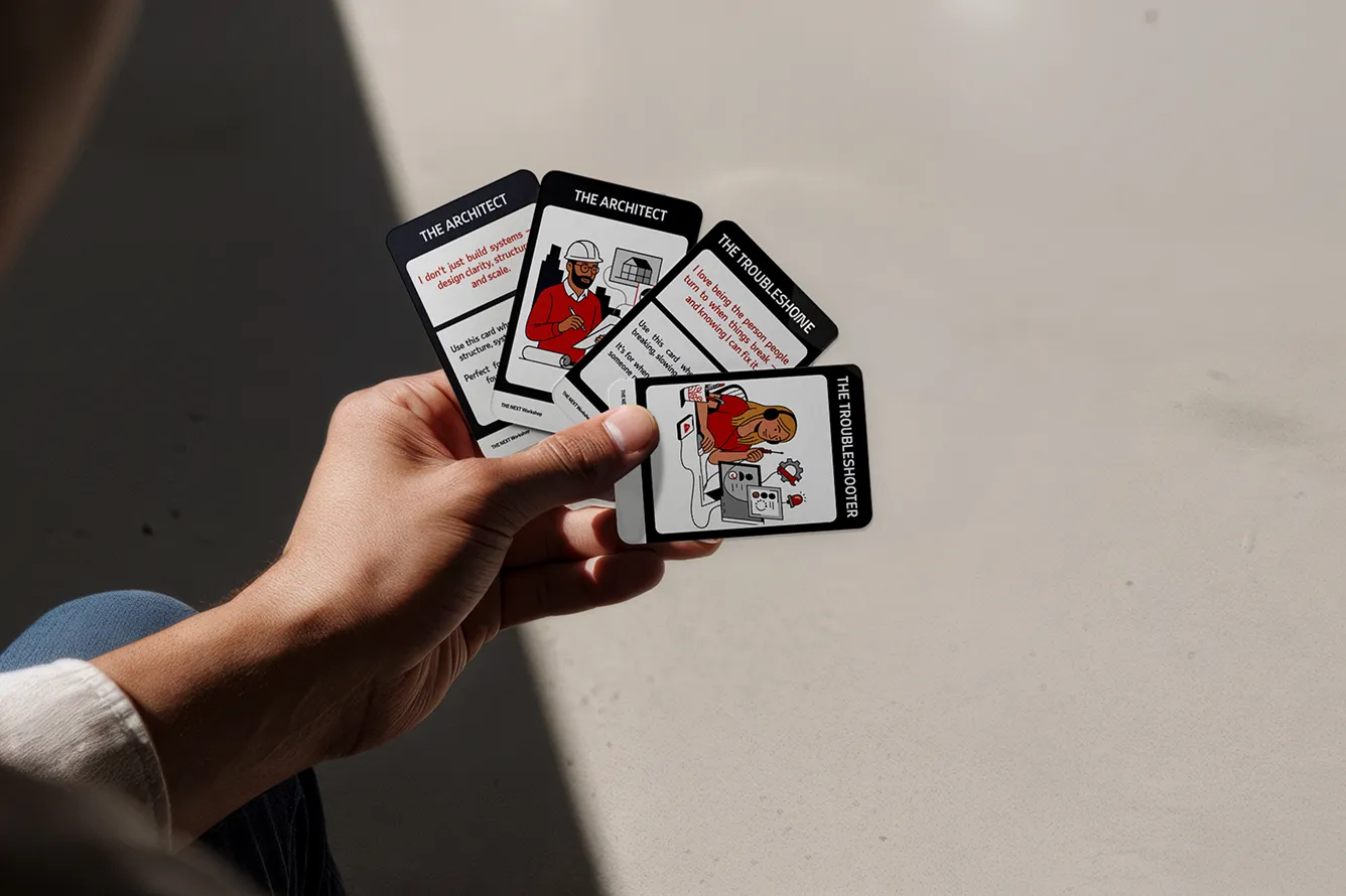 Hand holding four illustrated cards with titles The Architect and The Troubleshooter, showing text and drawings of people.