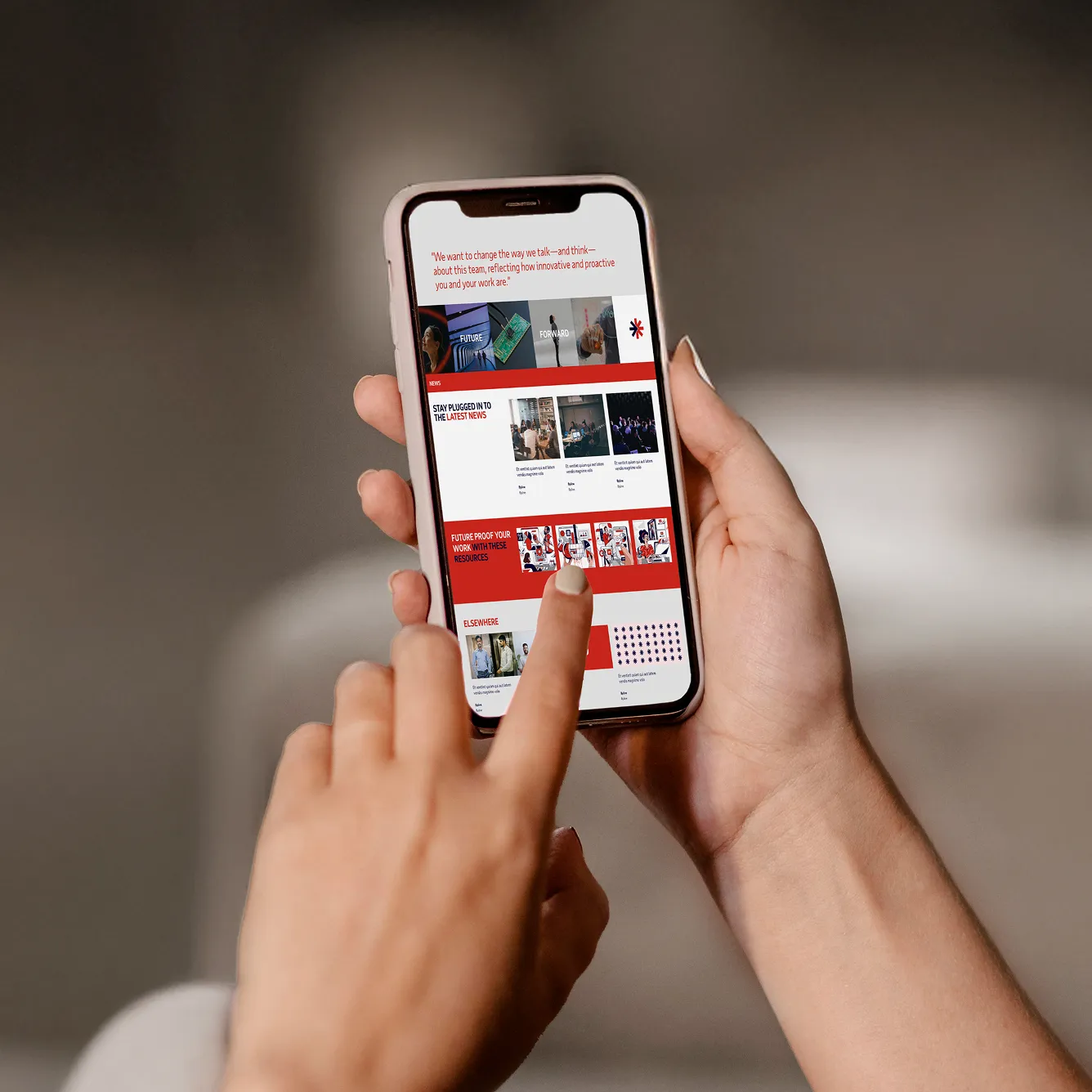 Person scrolling a red and white themed news and resources webpage on a smartphone.