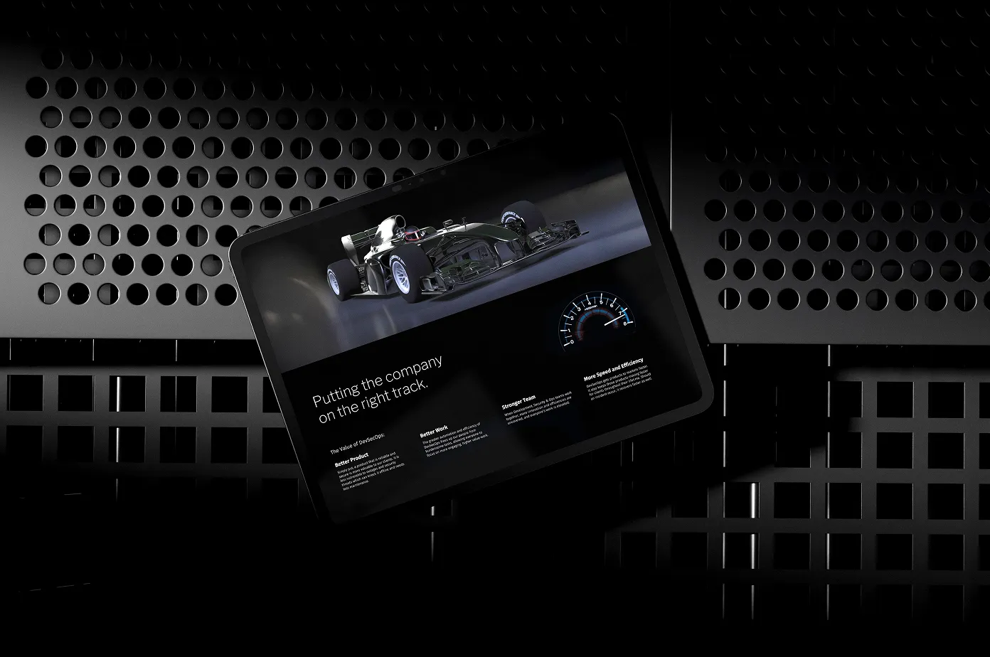Tablet displaying a racing car and text about putting the company on the right track, lying on a perforated black metal surface.