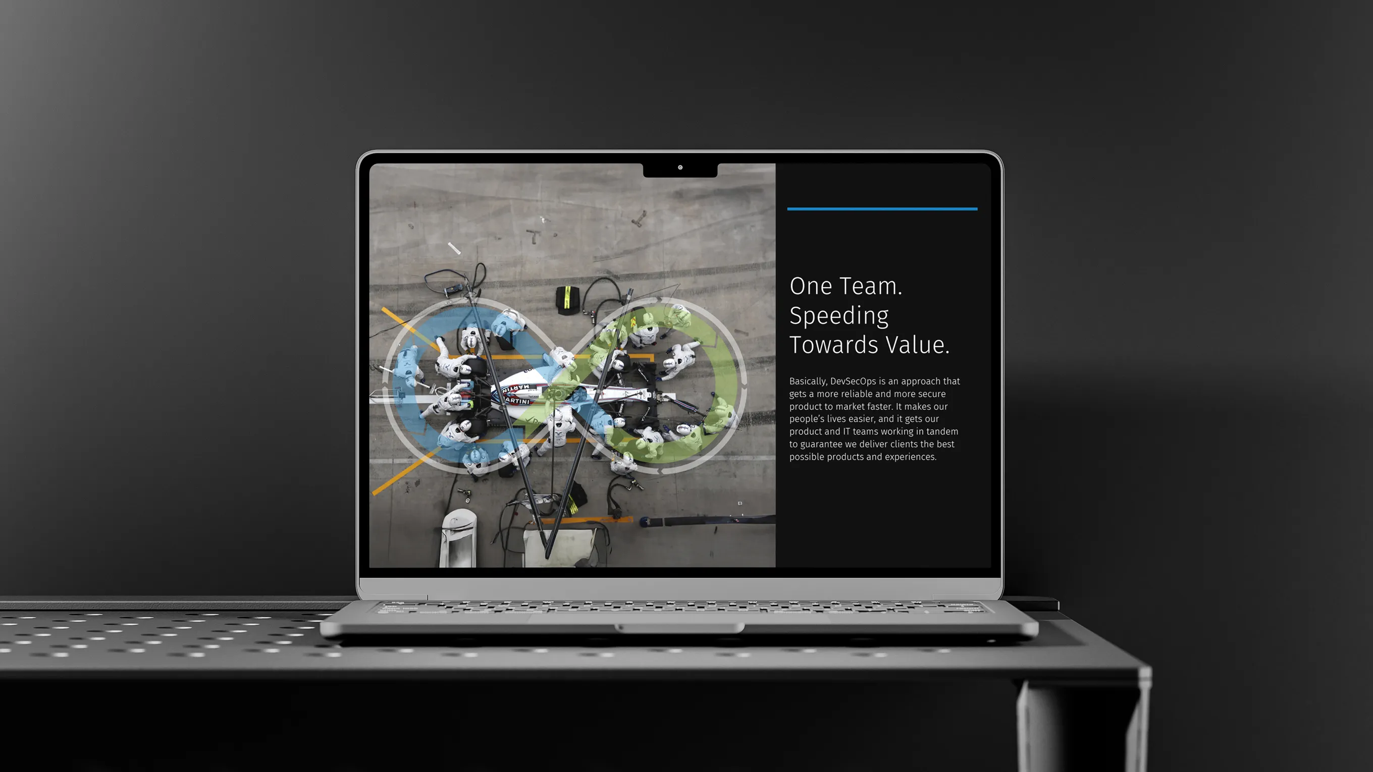 Laptop on a metal table displaying an overhead image of a racing pit crew working on a car with an infinity loop graphic overlay and text about DevSecOps speeding towards value.