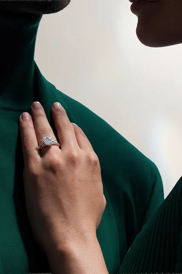 Close-up of a hand with an engagement ring resting on a person's chest wearing a green turtleneck.