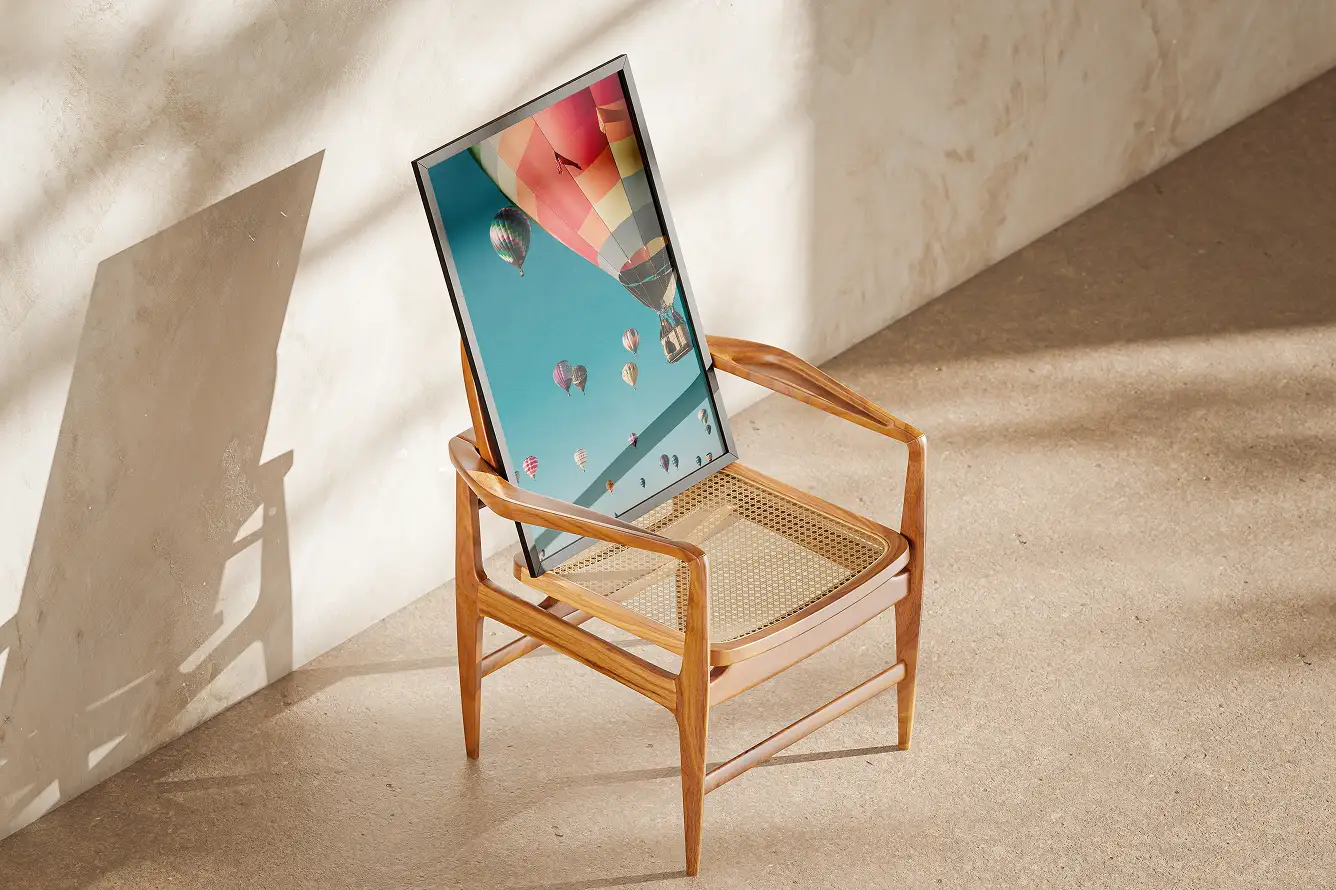 Wooden chair with woven seat holding a framed photo of colorful hot air balloons against a clear blue sky.