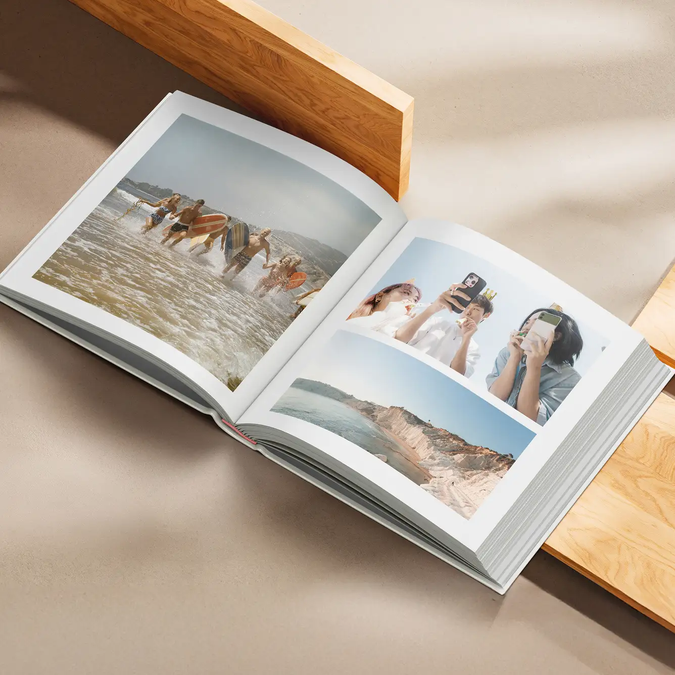 Open photo book displaying images of friends running in ocean waves, three people taking selfies, and a coastal cliff landscape.