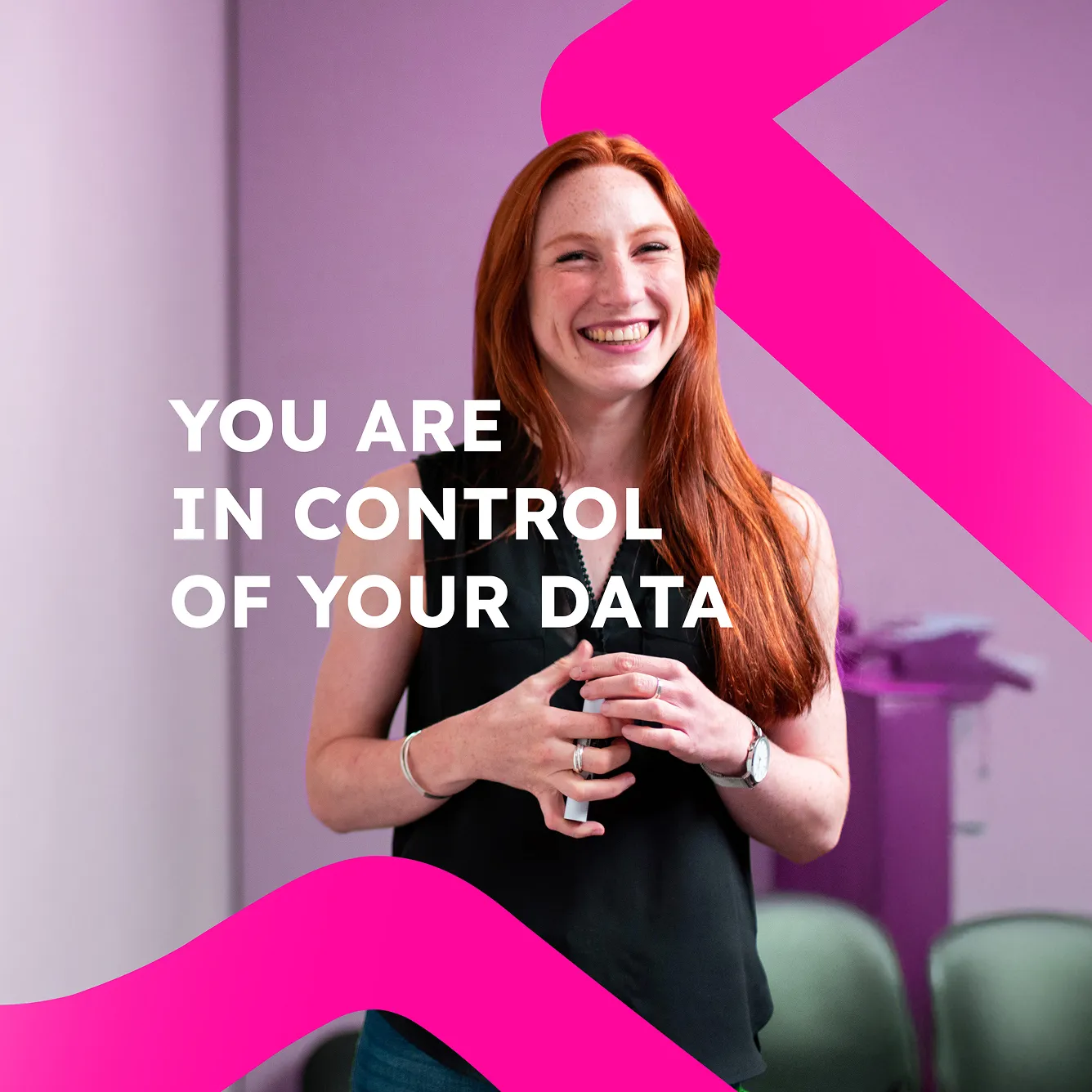 Smiling red-haired woman in a black sleeveless top standing in front of a purple background with text 'You are in control of your data'.