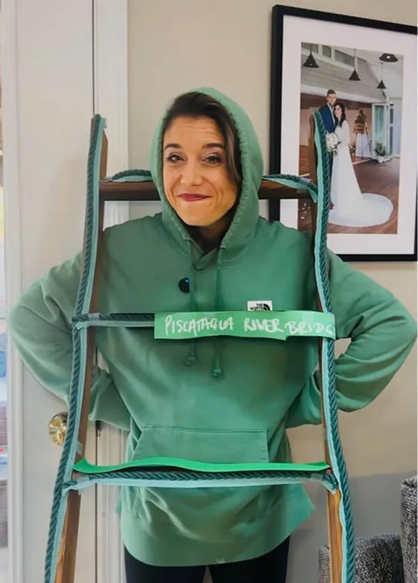 Katie Zarrilli in a green hoodie stands behind a rope ladder labeled 'Piscataqua River Bridge'.