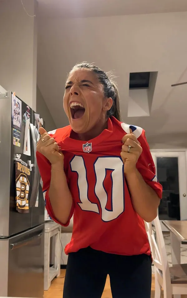 Katie Zarrilli wearing a red NFL jersey with number 10 cheering.