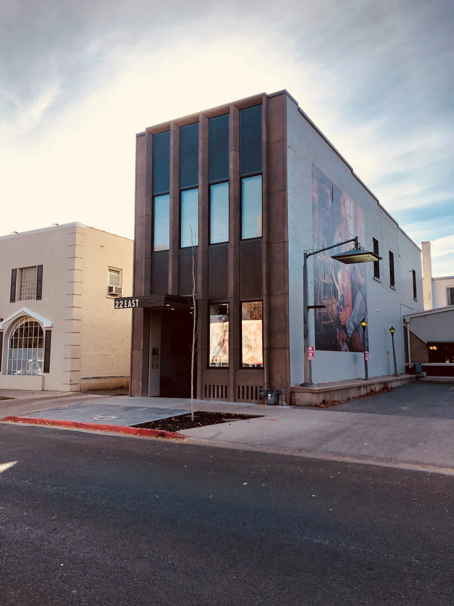 Modern two-story building with vertical windows and a sign reading '22 EAST' above the entrance under a bright sky.