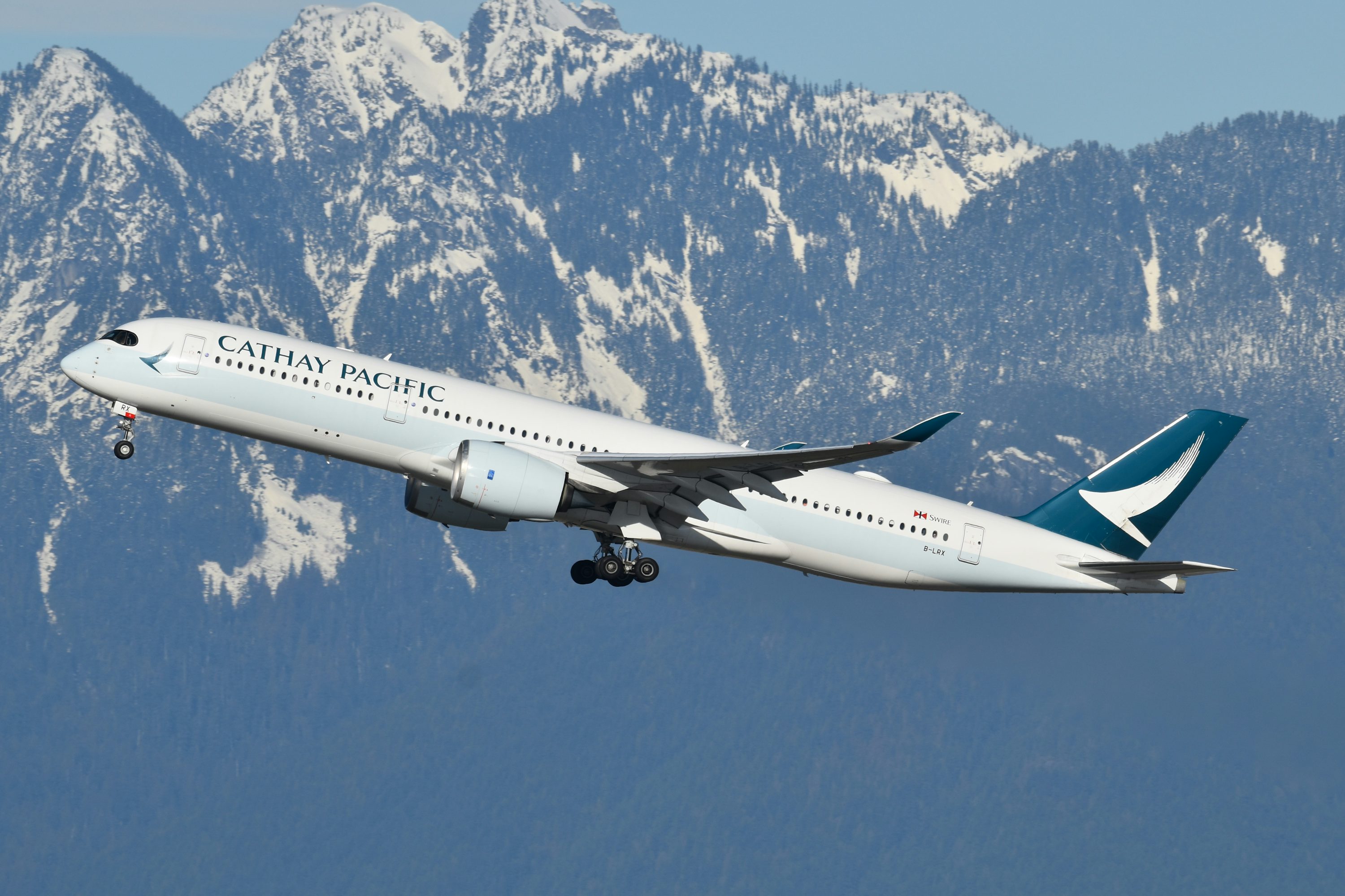 A large jetliner flying over a mountain range