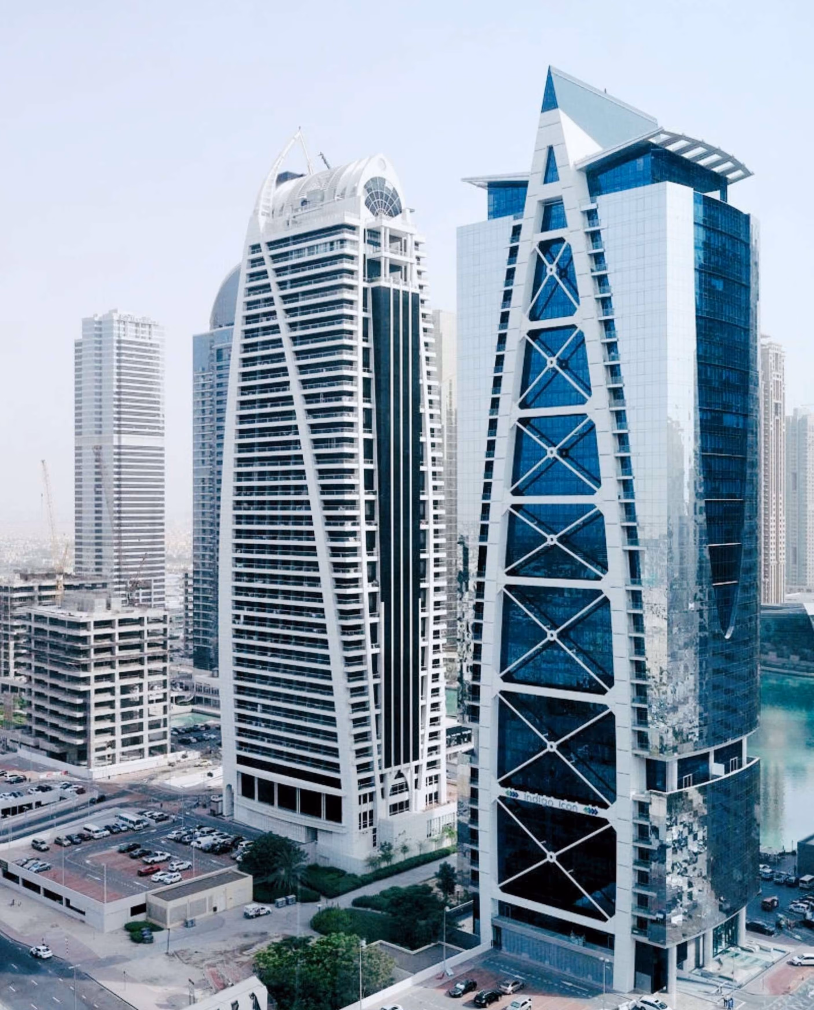 Cityscape featuring modern high-rise buildings with unique architectural designs near a water body.