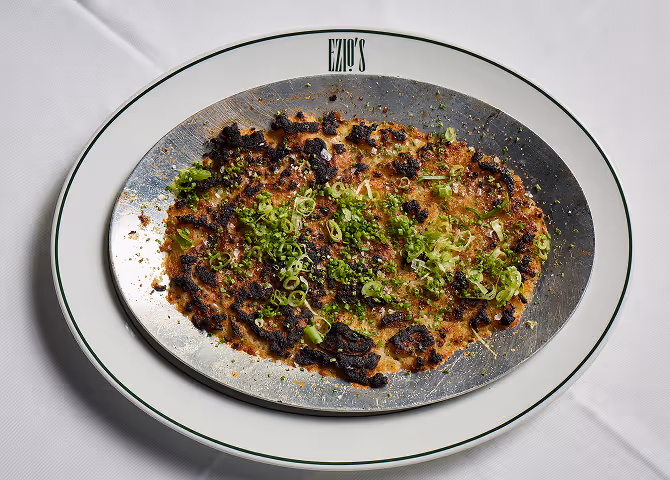 Gourmet grilled octopus with fresh herbs served on a metal and porcelain plate.