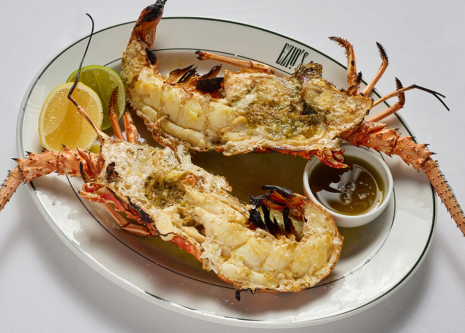 Gourmet grilled lobster dish with lemon wedges and dipping sauce.
