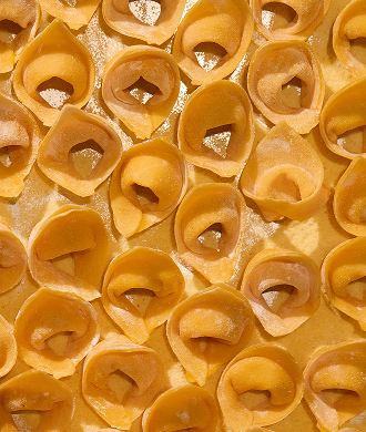 Top-down view of fresh artisanal tortellini pasta arranged on a floured surface.