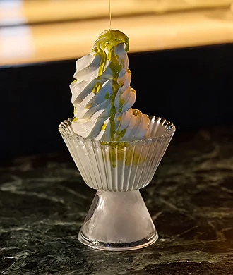 Soft serve vanilla ice cream in a glass bowl topped with olive oil drizzle.