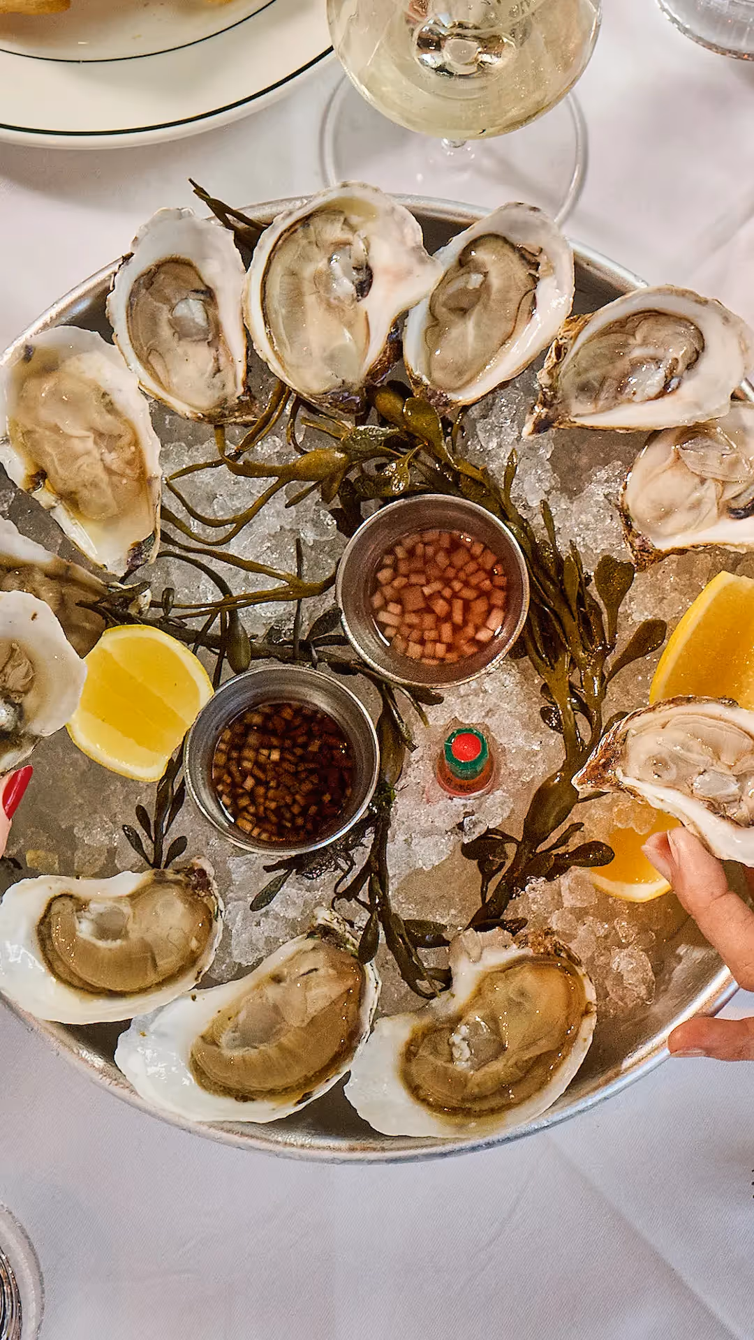 Fine dining restaurant interior featuring white tablecloths, dark chairs, and a large artistic purple chandelier hanging from the ceiling.
