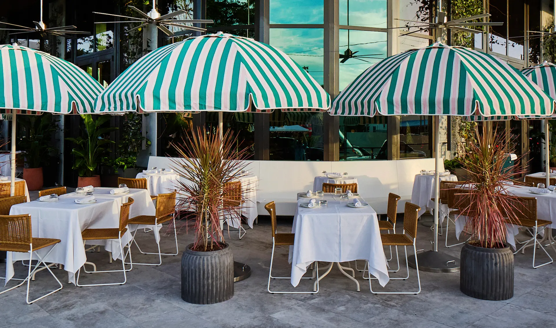 Luxurious terrace with an infinity pool, lounge chairs under a red umbrella, and a panoramic view of the ocean and city skyline.
