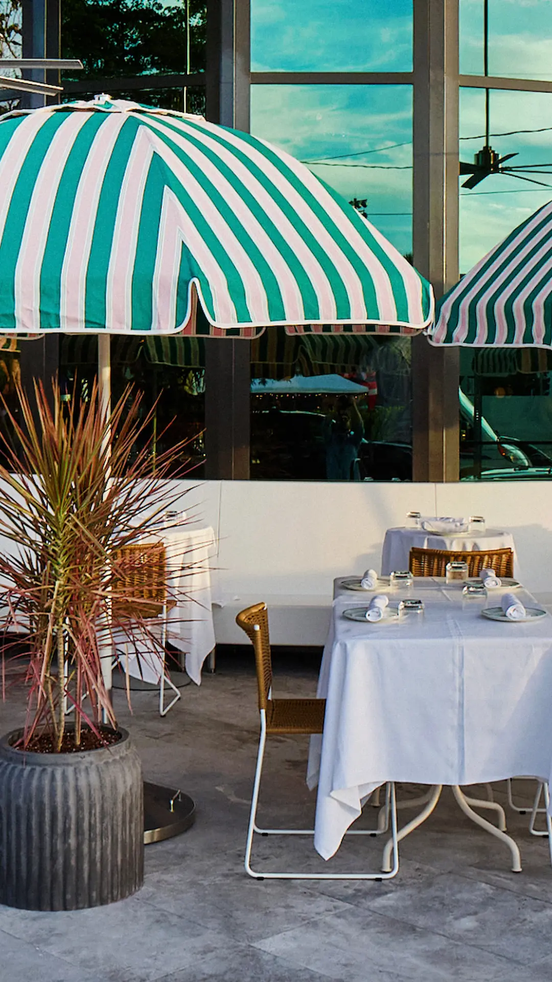 Luxurious terrace with an infinity pool, lounge chairs under a red umbrella, and a panoramic view of the ocean and city skyline.