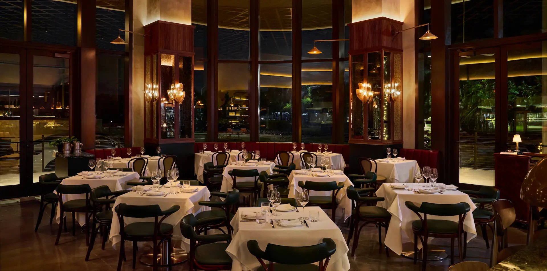Fine dining restaurant interior featuring white tablecloths, dark chairs, and a large artistic purple chandelier hanging from the ceiling.