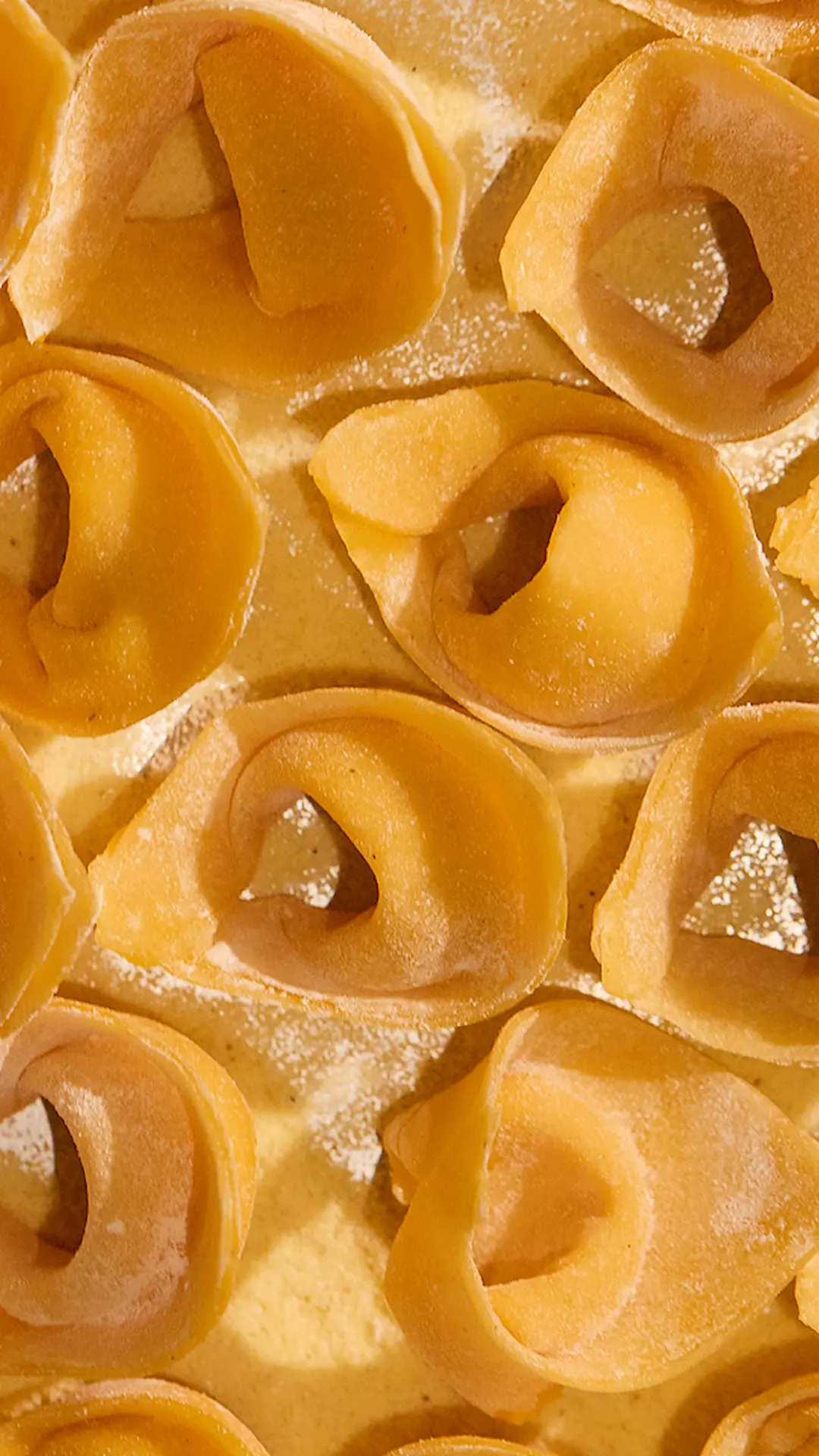 Sliced grilled tomahawk steak served on a silver platter with roasted garlic and sides, surrounded by fresh oysters and shrimp cocktail on a white tablecloth in a luxury steakhouse setting.