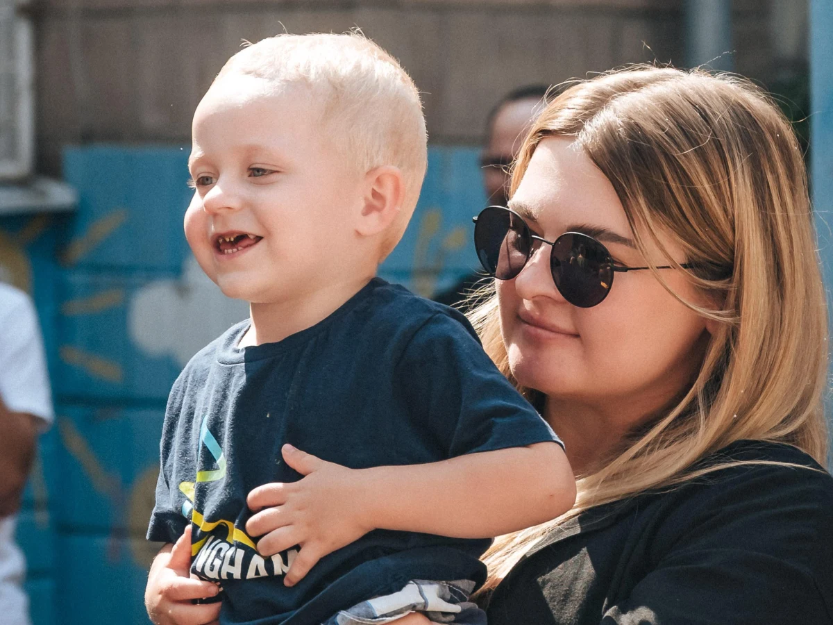 Волонтерка тримає на руках маленьку дитину під час благодійного заходу.