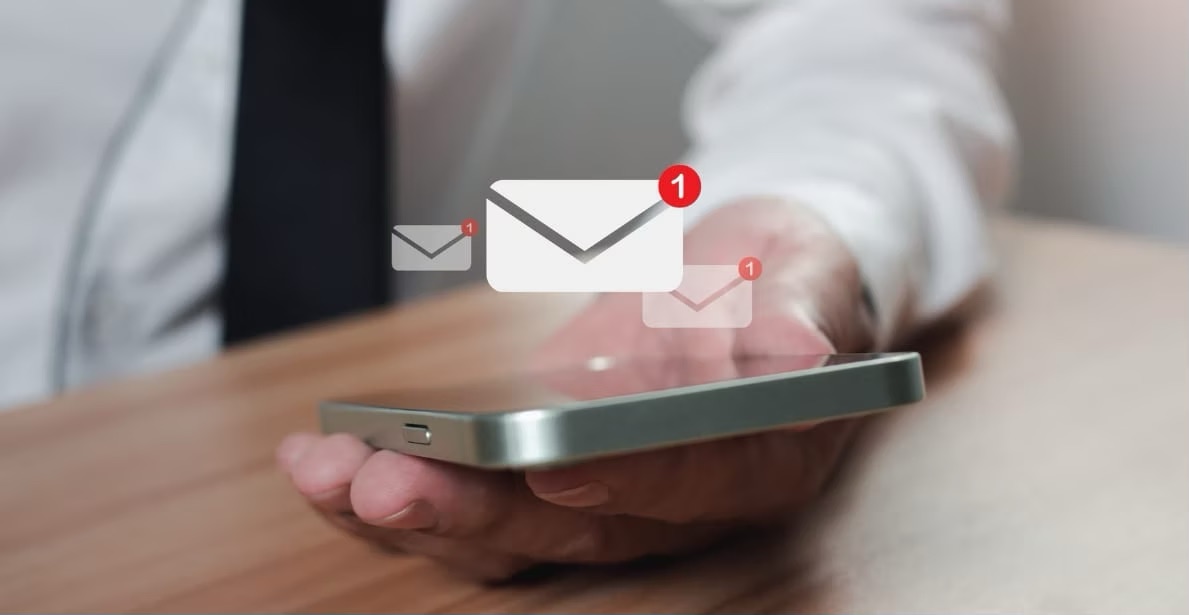 Photo of a hand holding a phone with floating envelope notification icons, representing email engagement.