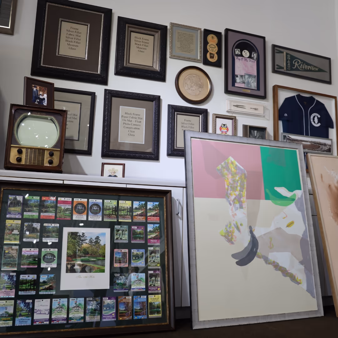 Wall display of various framed photos, certificates, golf memorabilia, and a retro television set, with large framed artwork leaning against the wall.