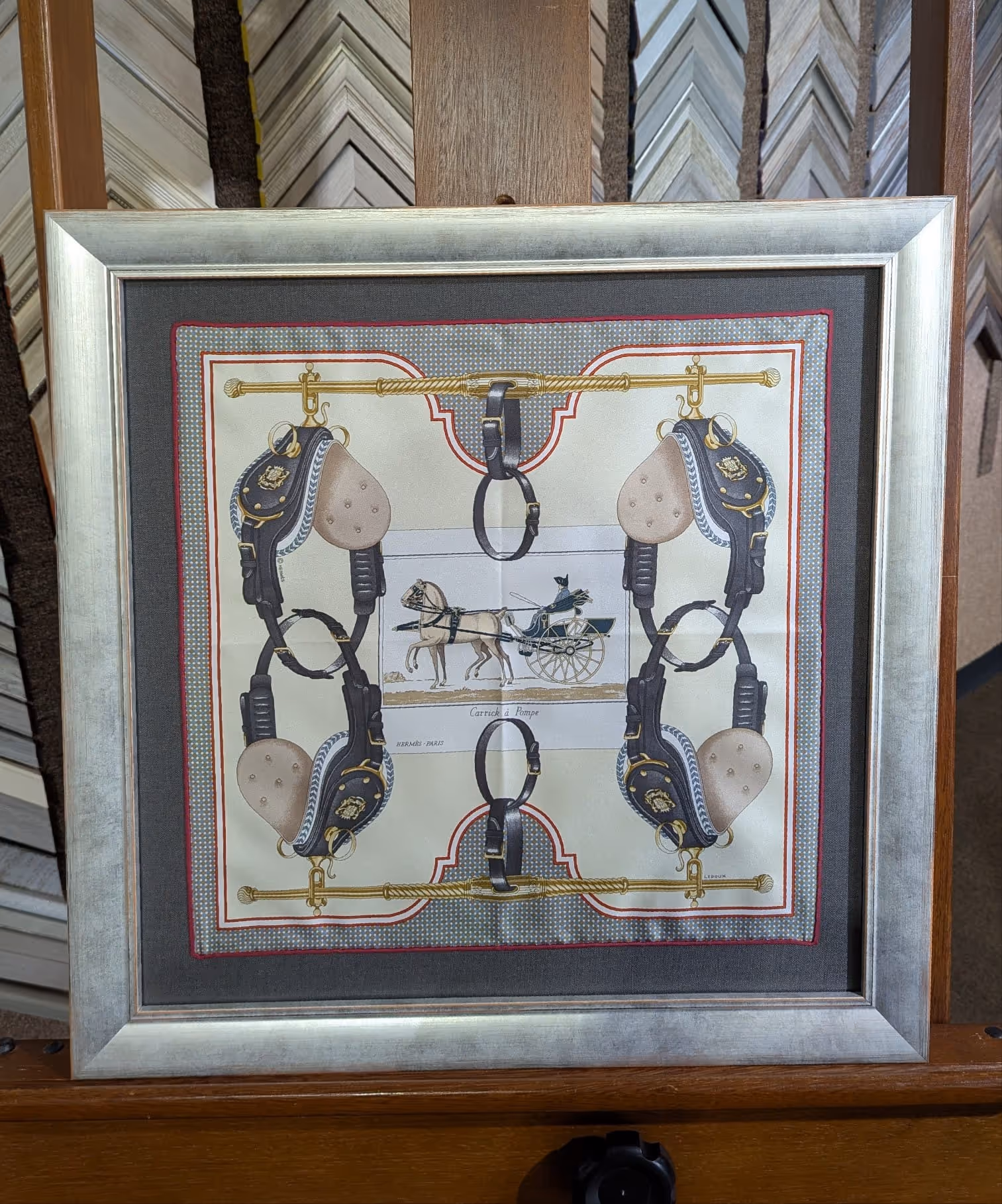 Framed silk scarf with equestrian design featuring horse harnesses and a horse-drawn carriage illustration in the center.