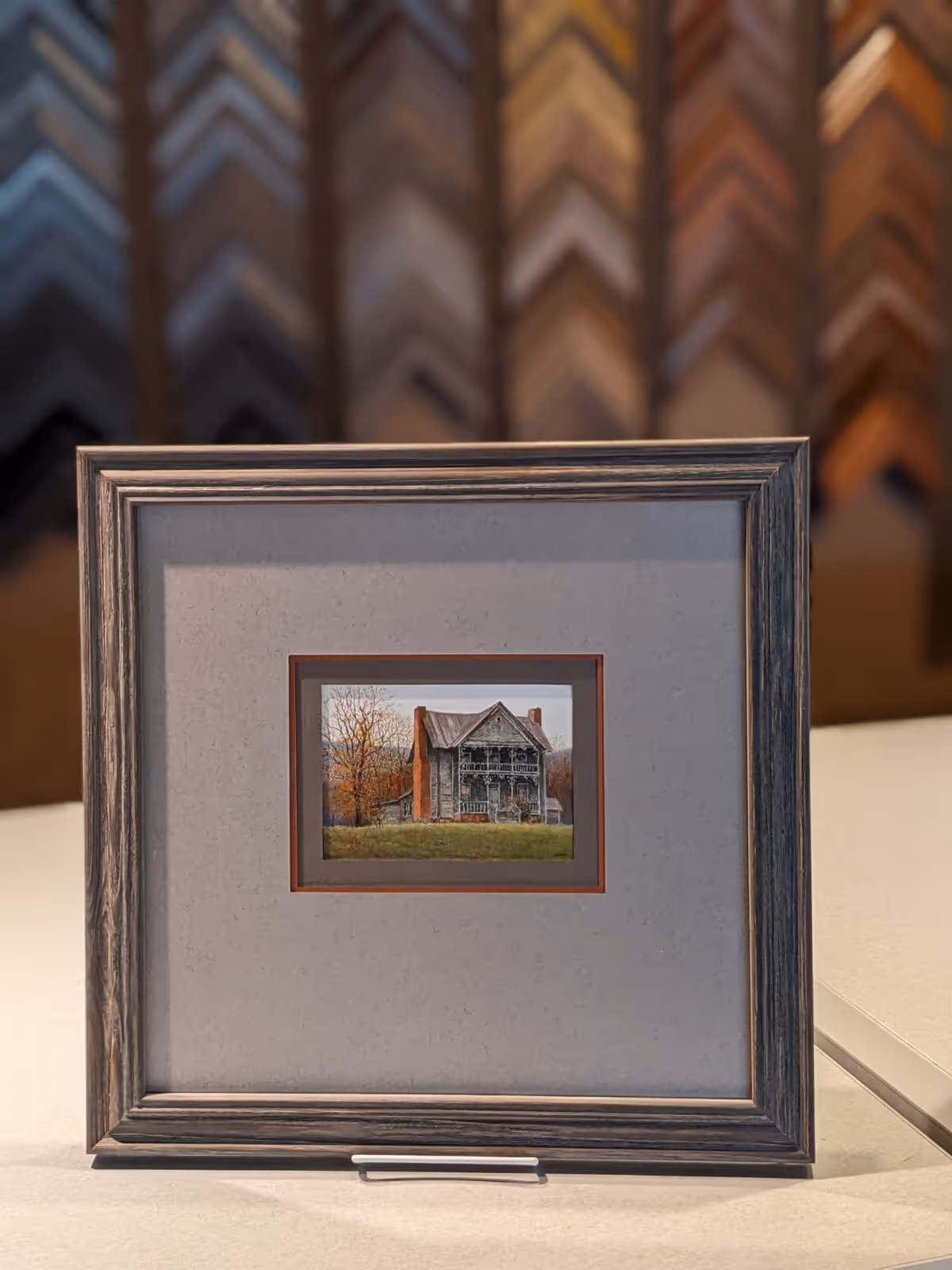 Framed miniature painting of an old two-story farmhouse with a porch and autumn trees in the background.