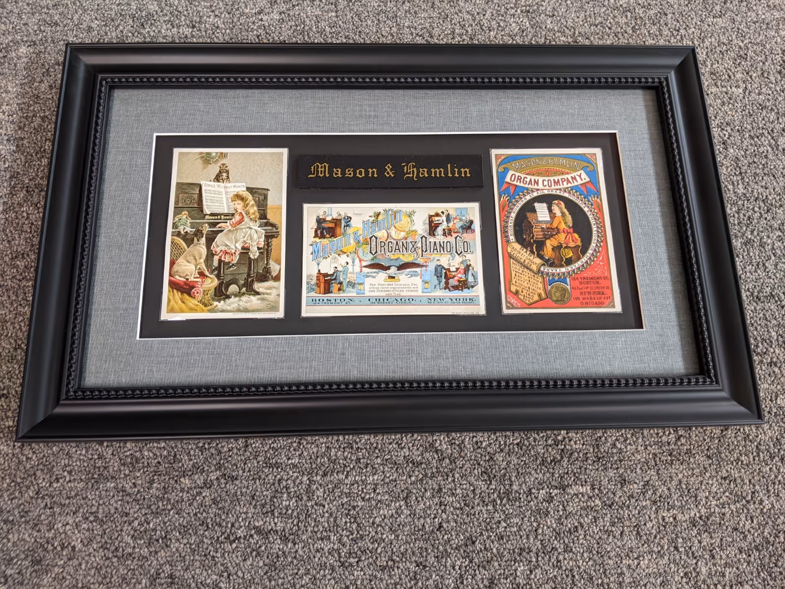 Framed Mason & Hamlin memorabilia featuring three vintage illustrations including a girl at a piano with a dog, a colorful company logo, and a woman playing an organ.