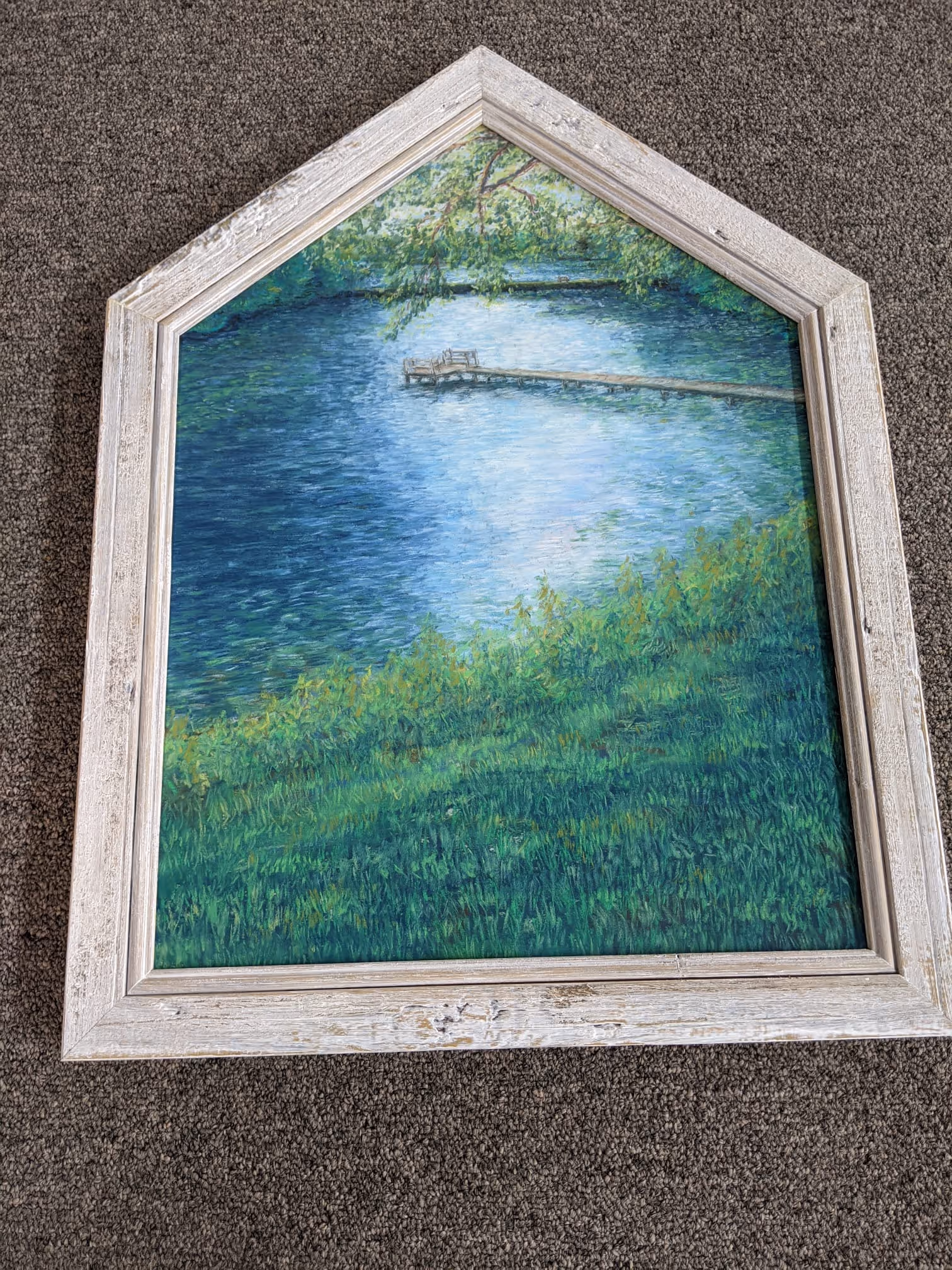 Framed painting of a pond with a wooden dock extending into the water, surrounded by green grass and overhanging tree branches.