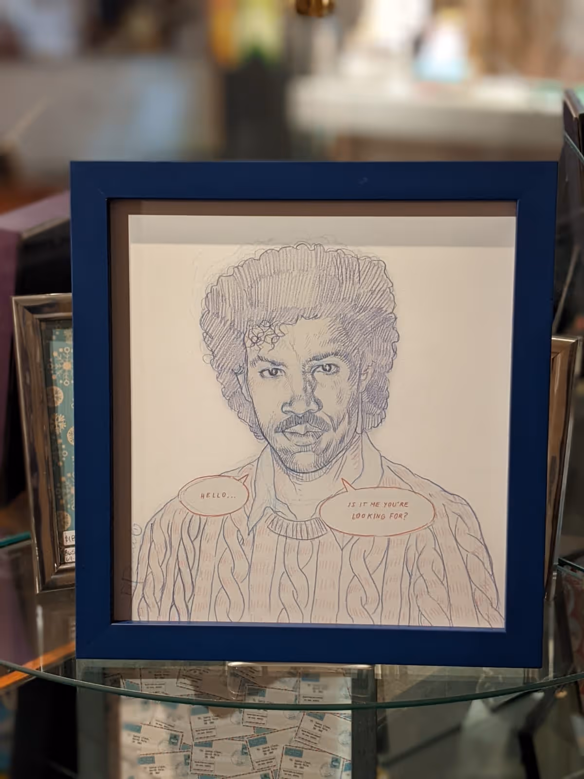 Framed pencil sketch of a man with curly hair and a mustache saying, 'Hello... Is it me you're looking for?' in speech bubbles.