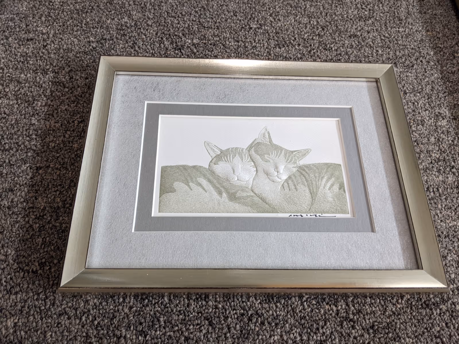 Framed drawing of two sleeping cats cuddled together on a textured carpet.