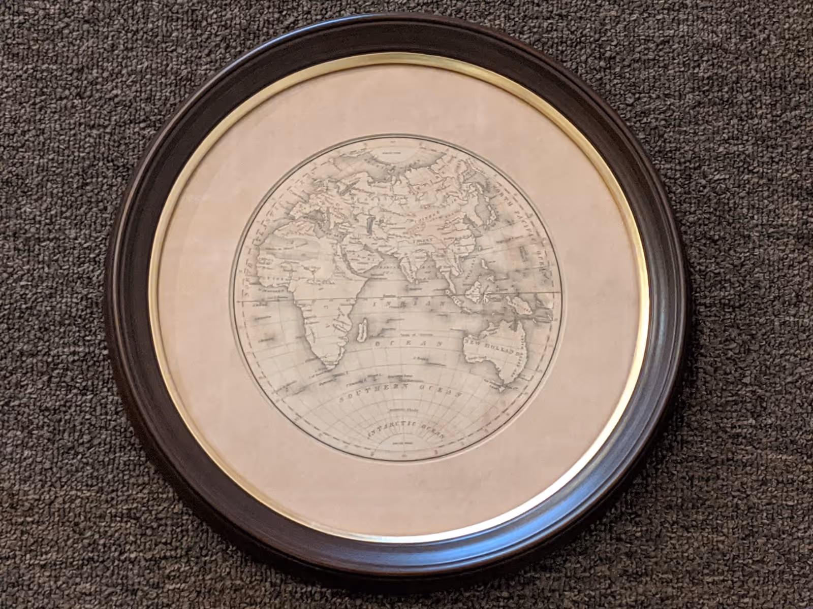 Framed vintage map showing Africa, the Middle East, and parts of Asia and Australia on a textured gray surface.