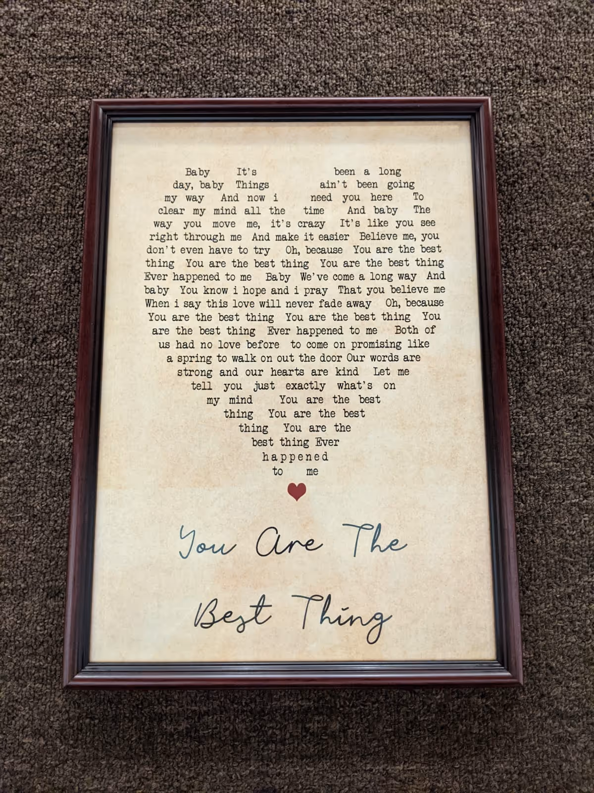 Framed poem shaped like a heart with typed text about love, ending with a small red heart and the handwritten phrase 'You Are The Best Thing' on beige paper.