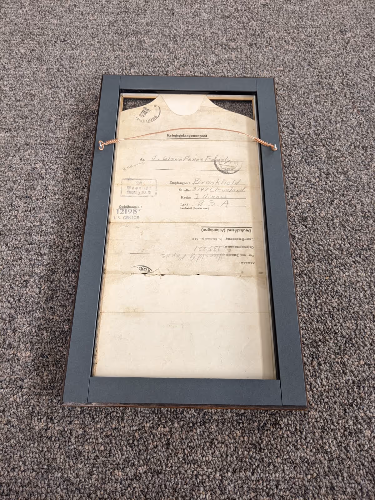 Framed old handwritten letter addressed to J. Glenn Peirce in Brookfield, Illinois, USA, displayed on a gray carpet.