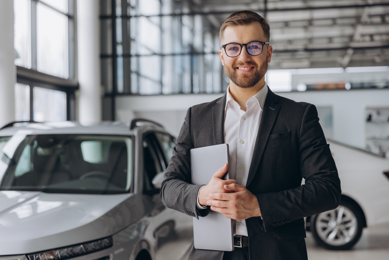 Car Dealer in front of a car, smiling