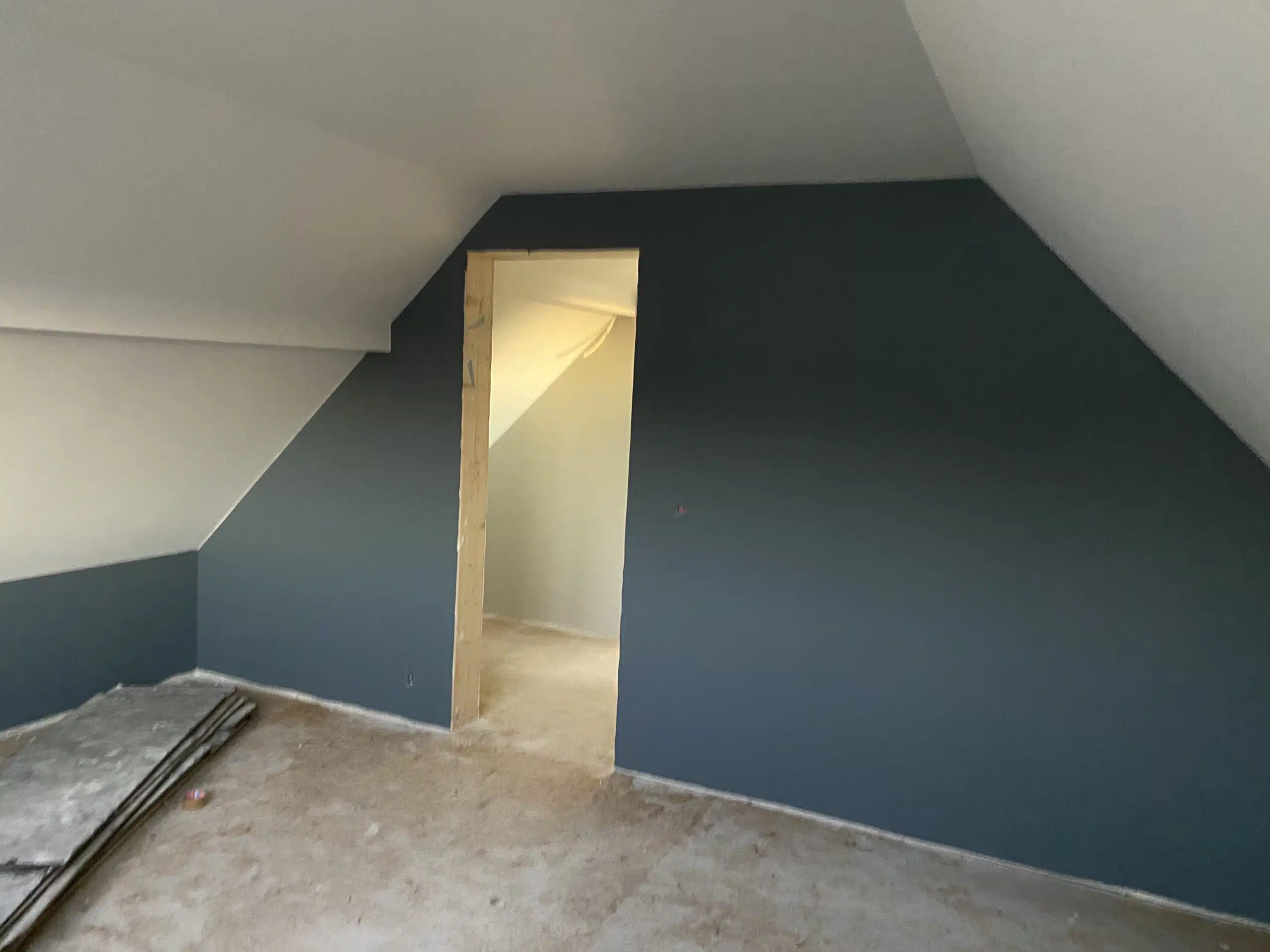 Et rom under oppussing med blåmalte vegger og åpen dør som fører til et annet rom.