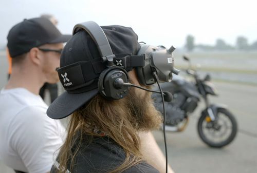 2 pilotes de drone fpv assis devant une moto