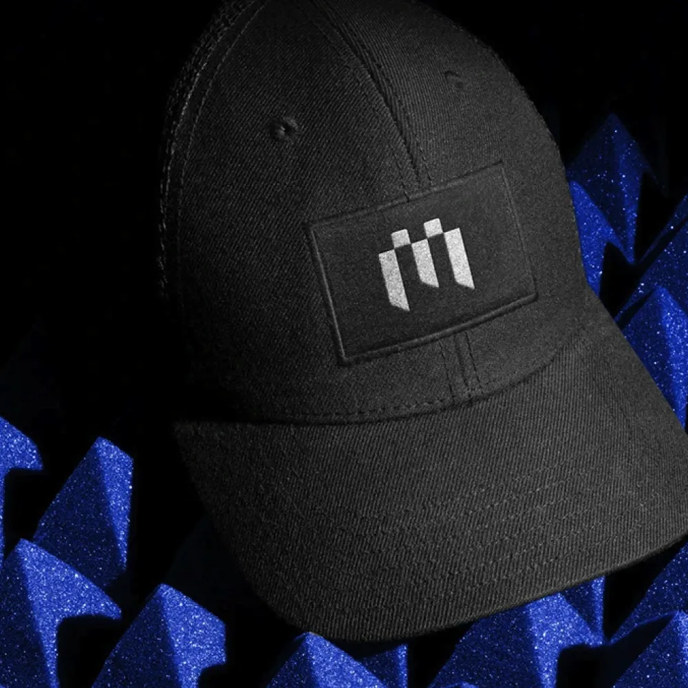 Gorra negra con parche frontal que presenta un diseño en blanco con barras verticales, manteniendo coherencia con el sistema visual de la marca. Servicio de banding, ubicación México.