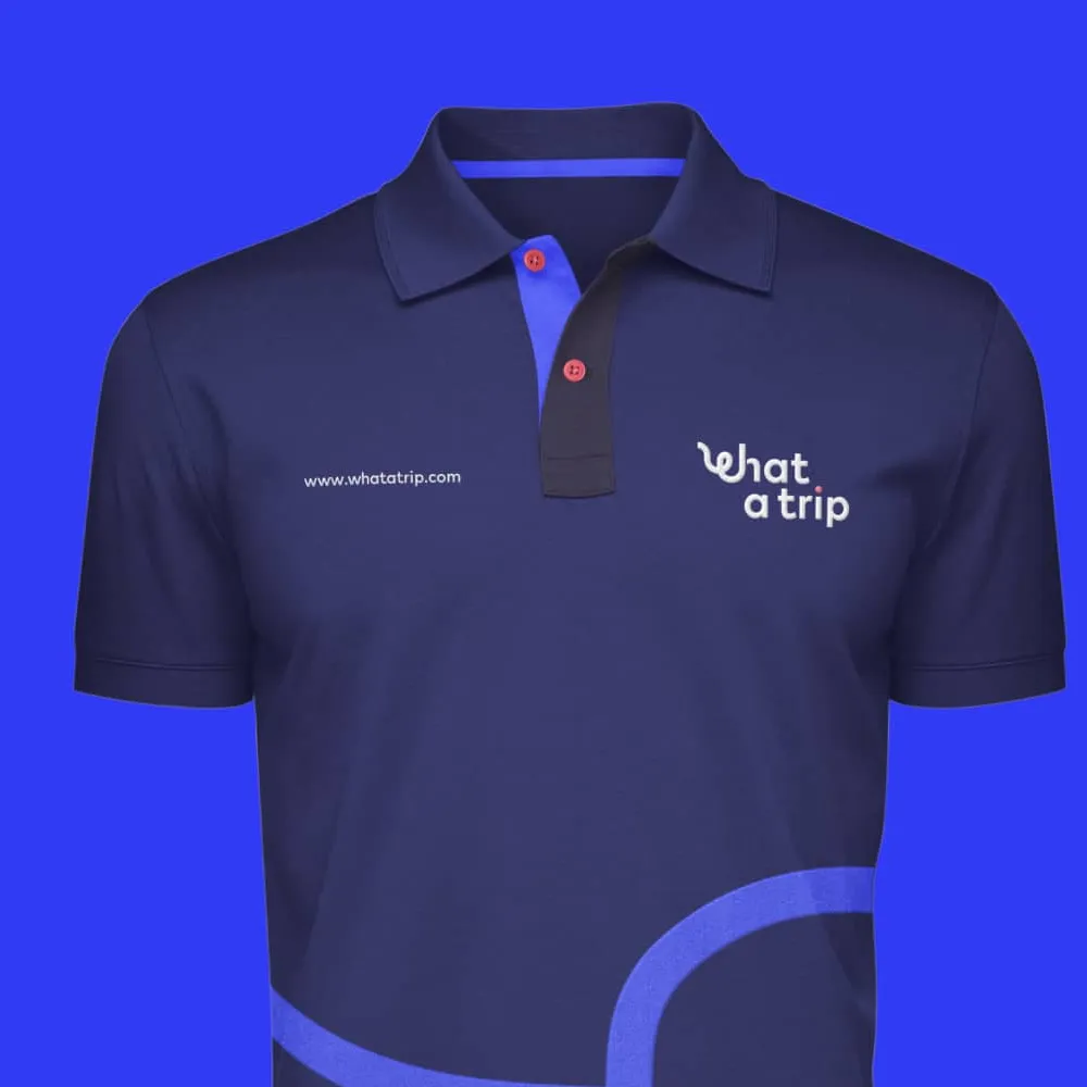 Polo azul marino con botones rojos, logo 'what a trip' y texto del sitio web en el pecho. Servicio de branding, ubicación Cusco, Perú.