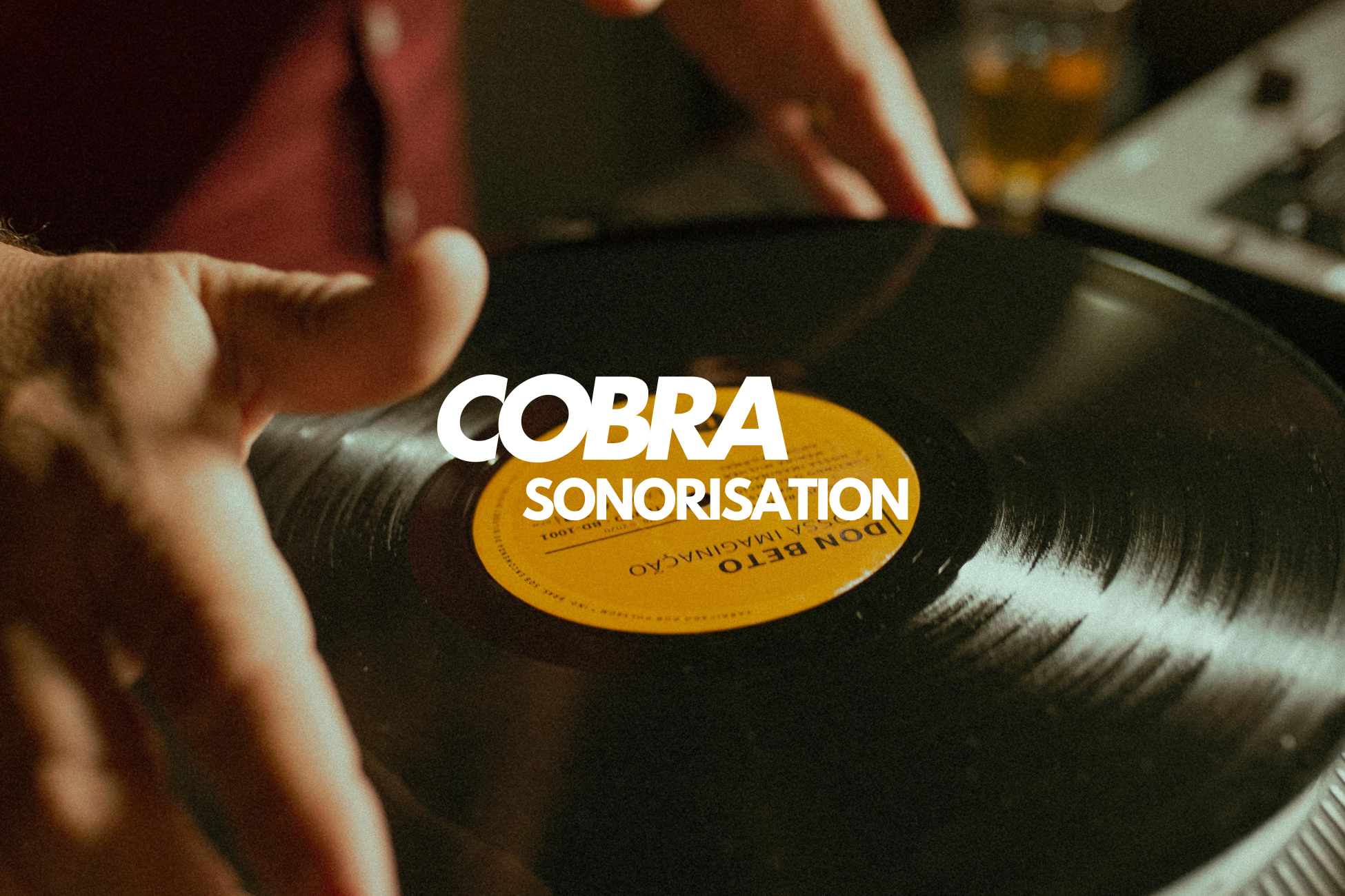 Mains d'un DJ manipulant un disque vinyle noir avec une étiquette jaune sur une platine.