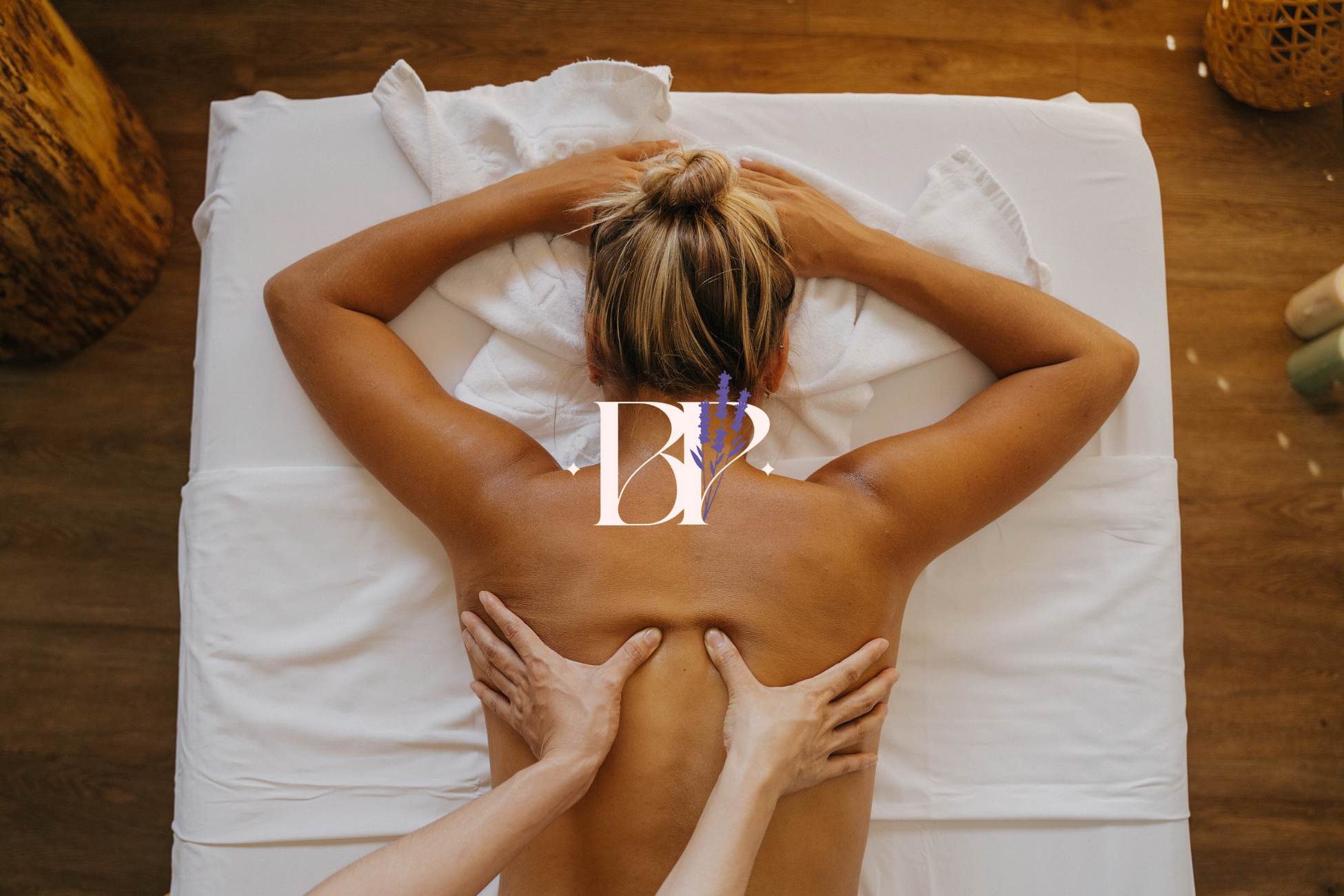 Personne allongée sur une table de massage recevant un massage du dos dans un spa avec drap blanc.