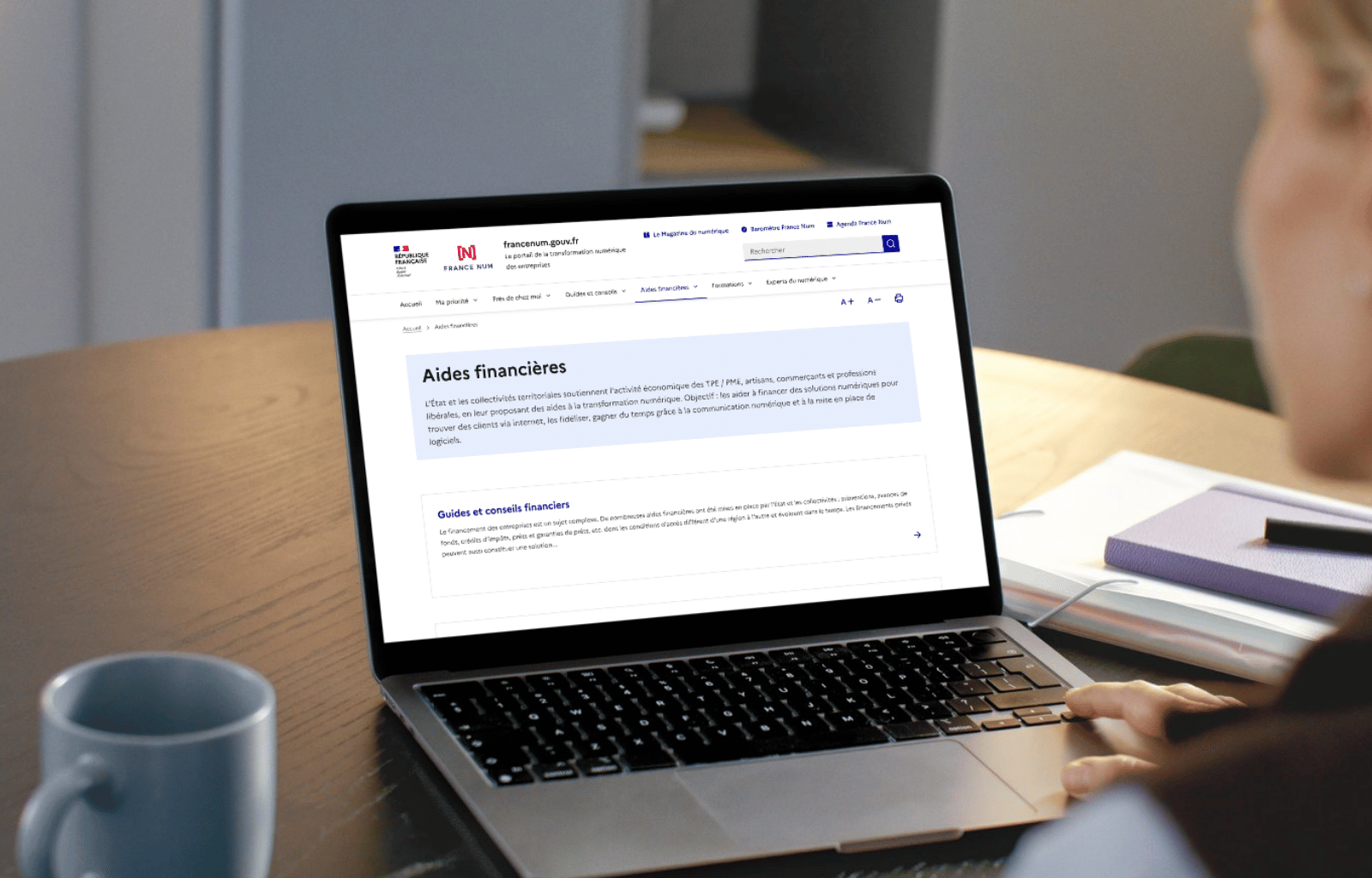 Personne utilisant un ordinateur portable affichant une page web sur les aides financières pour les entreprises sur le site francenum.gouv.fr.
