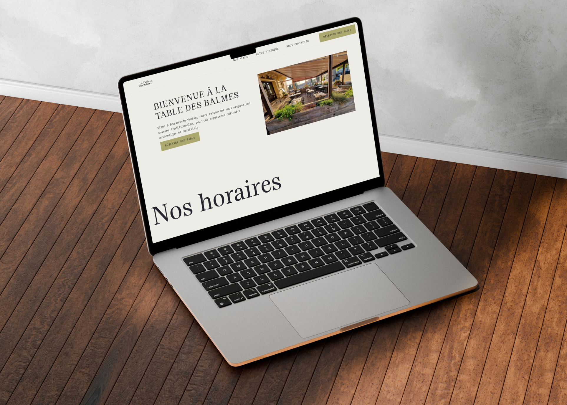 Ordinateur portable affichant la page d'accueil du site La Table des Balmes avec photo de terrasse et texte de bienvenue en français.