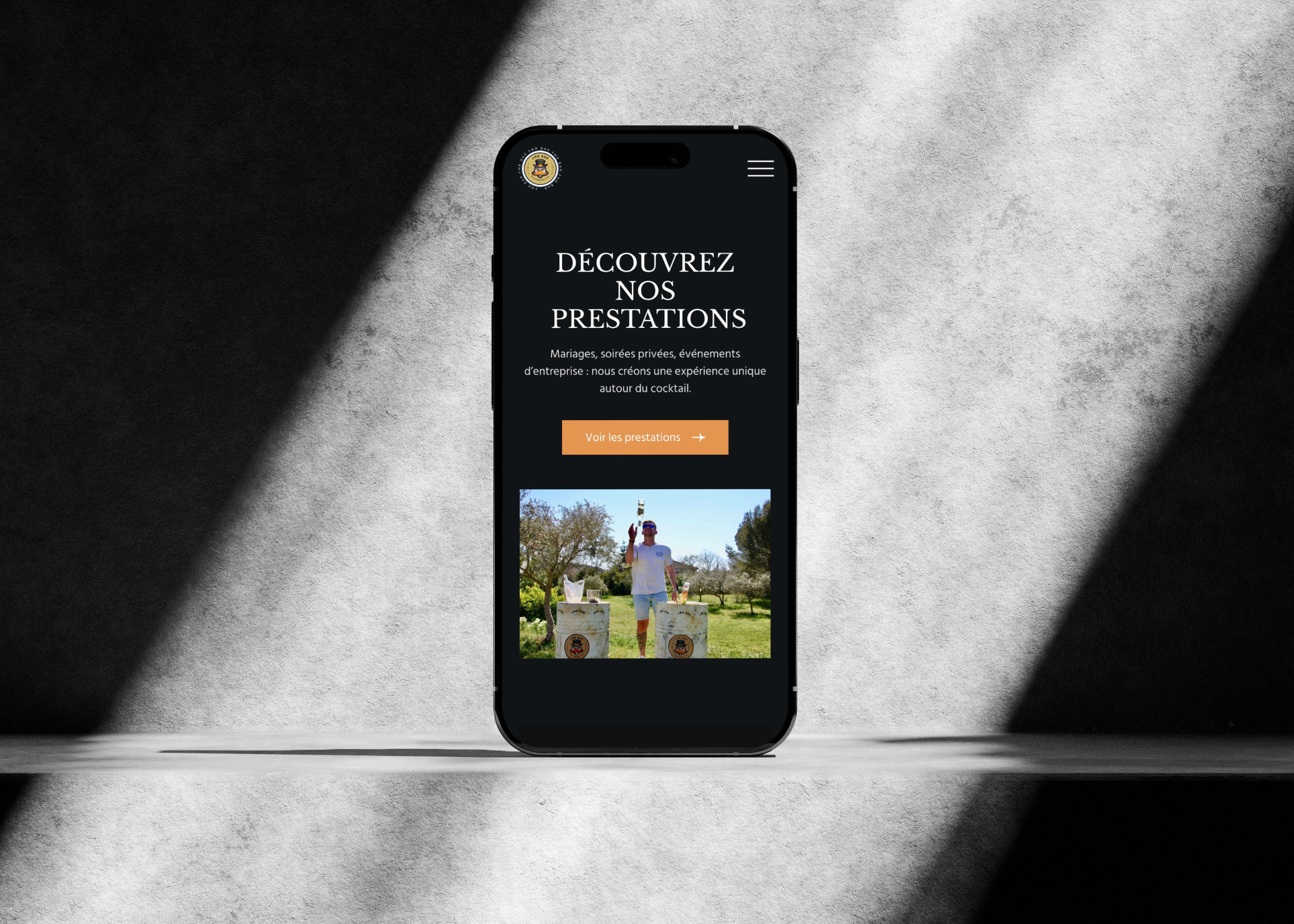 Téléphone affichant une page web avec le texte 'Découvrez nos prestations' et une image d'un homme lançant une bouteille lors d'un événement en extérieur.
