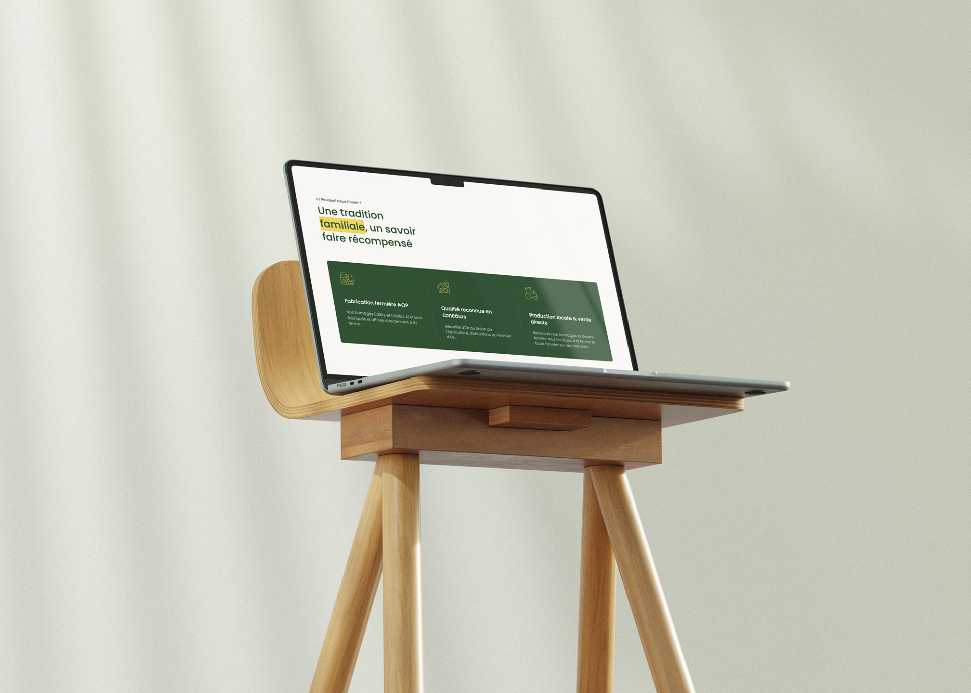 Ordinateur portable ouvert posé sur un tabouret en bois clair avec écran affichant un texte en français sur une tradition familiale et production locale.